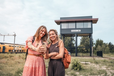 Twee vrouwen maken een selfie bij een treinstation