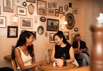 Twee vrouwen lachen naar elkaar in een cafe