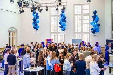 Mensen staan in de Muntzaal met elkaar te praten