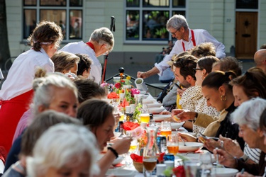 Een groep mensen die aan lange tafels zitten